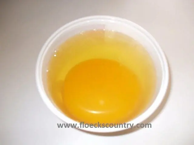 A cup filled with yellow-orange liquid, likely juice or broth.